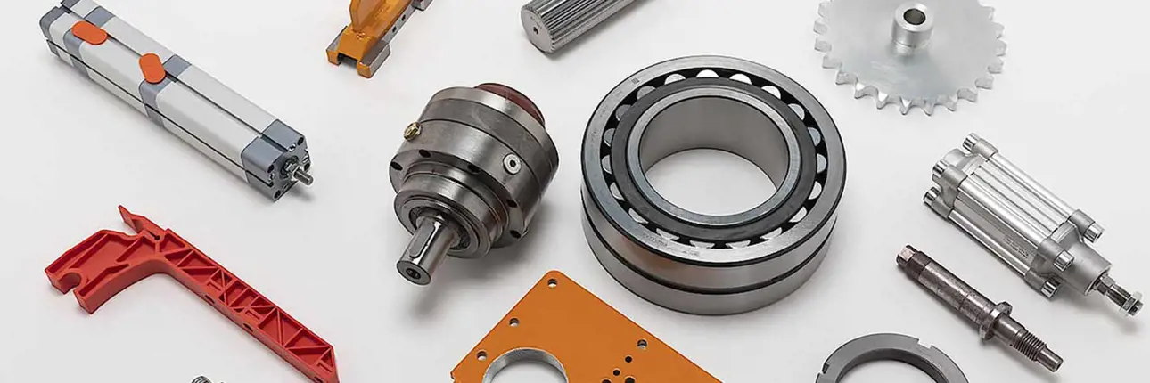 A collection of mechanical components and industrial machine parts, including a bearing, gear, piston cylinder, and various metal and plastic elements, arranged on a white background.
