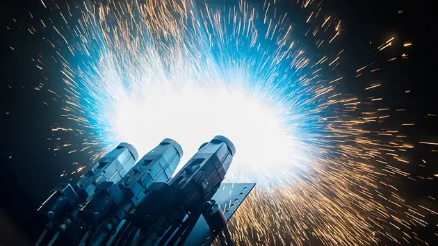 Close-up of the Yankee dryer during the metallizing process, with bright sparks flying in all directions against a dark background.