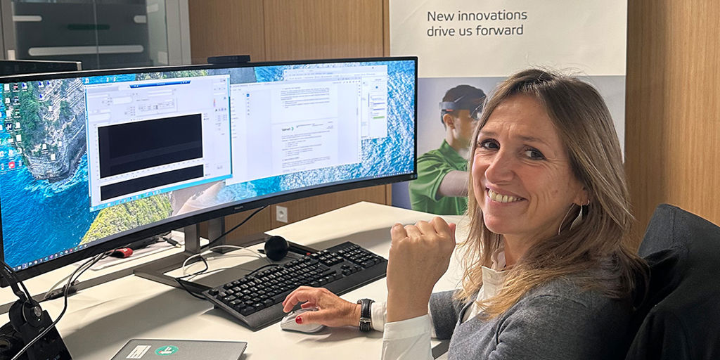 A woman sitting on computer and working while smiling to the camera.