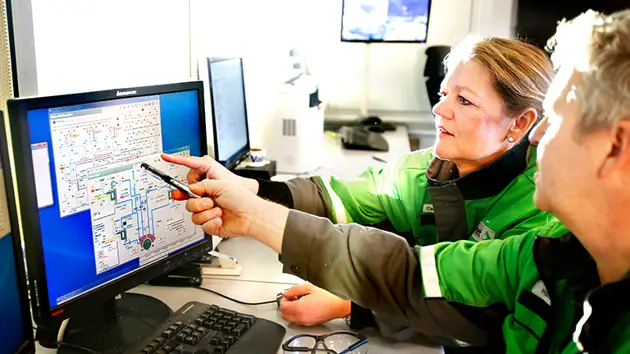 Two people in green Valmet jackets looking at a computer at the Tissue Technology Center.