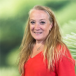 Smiling women in a red top standing infront a green studio screen